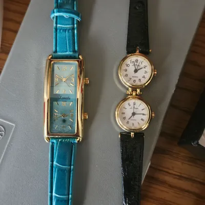 Sale Photo Thumbnail #52: Two dual-time women's quartz wristwatches, including a rectangular Xanadu watch with a teal leather strap and a round Le Baron watch with a black leather strap.