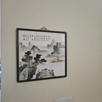 Sale Photo Thumbnail #104: Framed Chinese porcelain tile plaque featuring a hand-painted landscape scene with calligraphy and red seal stamps, set in a dark wood frame with a brass hanger.