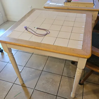 Sale Photo Thumbnail #38: Square tile-top accent table with off-white painted legs and a light wood trim, showing minor wear around the edges.
