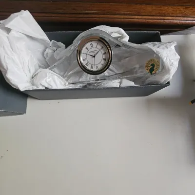 Sale Photo Thumbnail #27: Waterford crystal desk clock packed in its original box with tissue paper and gold foil seahorse decal, featuring a white face with Roman numerals.