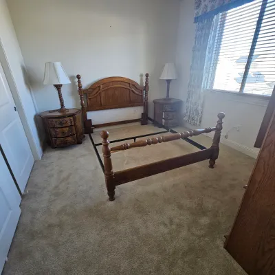 Sale Photo Thumbnail #77: Traditional wooden queen bed frame with turned posts, flanked by matching nightstands and table lamps.