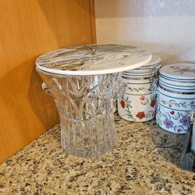 Sale Photo Thumbnail #37: Heavy cut crystal vase supporting a decorative round thermometer face, alongside floral ceramic kitchen canisters on a granite countertop.