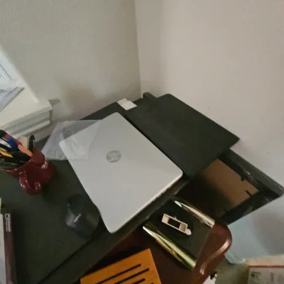 Sale Photo Thumbnail #99: Silver HP laptop resting on a desk converter alongside a computer mouse and desk accessories.