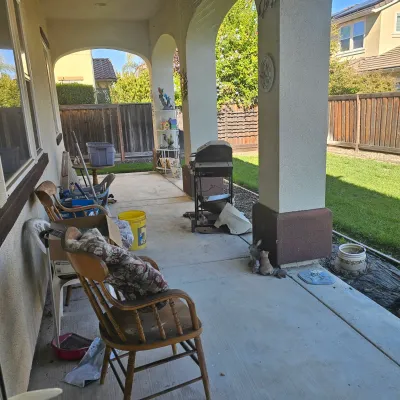 Sale Photo Thumbnail #39: Covered concrete patio featuring wooden armchairs, outdoor decor, lawn ornaments, and a portable grill.