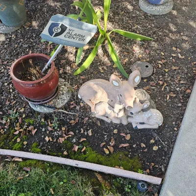 Sale Photo Thumbnail #110: Vintage ceramic deer garden statue featuring a doe resting with two fawns, positioned in a garden bed next to a glazed planter.