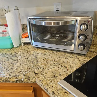 Sale Photo Thumbnail #35: Oster stainless steel countertop toaster oven featuring multiple cooking settings, control knobs, and a glass door.