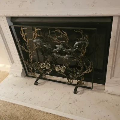 Sale Photo Thumbnail #91: Decorative metal fireplace screen with a nautical motif, featuring swimming dolphins and sea kelp designs, complete with built-in votive candle holders.
