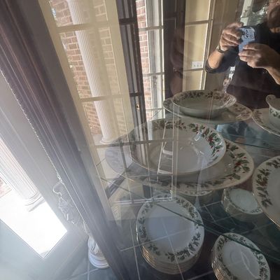 Sale Photo Thumbnail #153: Collection of holiday dinnerware with holly and ivy motifs displayed on glass shelves inside a china cabinet.