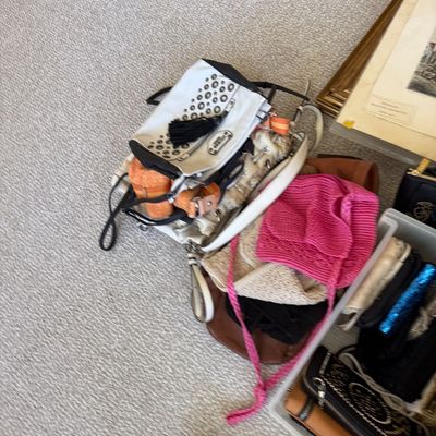 Sale Photo Thumbnail #178: Collection of assorted women's handbags and accessories, including a white studded Guess shoulder bag, woven hats, and leather wallets.