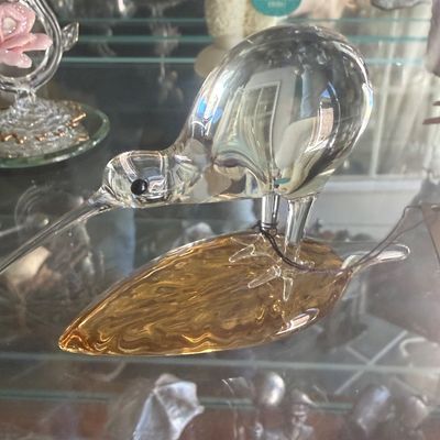Sale Photo Thumbnail #136: Hand-blown clear glass kiwi bird figurine standing on an amber glass leaf base, in excellent condition.