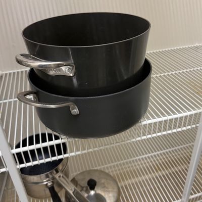 Sale Photo Thumbnail #84: Two stacked Circulon hard-anodized nonstick stockpots stored on wire shelving, with additional cookware below.