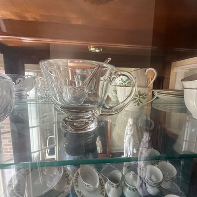 Sale Photo Thumbnail #155: Clear pressed glass pedestal punch bowl with matching ladle, displayed alongside holiday-themed china inside a glass cabinet.