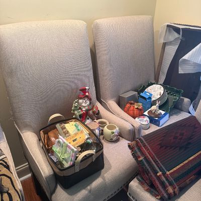 Sale Photo Thumbnail #115: Pair of contemporary high-back upholstered accent chairs with nailhead trim, holding various home decor items, holiday figurines, and a woven basket.