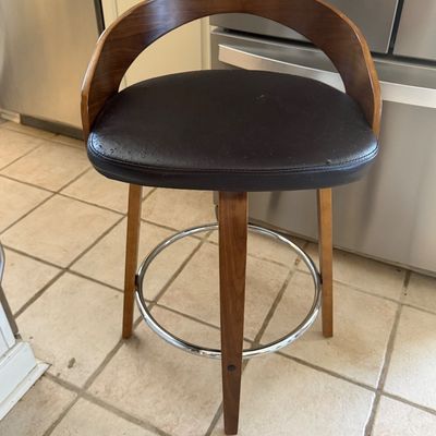 Sale Photo Thumbnail #87: Mid-century modern style swivel bar stool featuring a curved wooden backrest, dark faux leather cushioned seat, and a circular chrome footrest.
