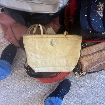 Sale Photo Thumbnail #168: Collection of assorted women's handbags resting on a carpeted floor, featuring a prominent yellow Coach leather tote alongside other branded purses.