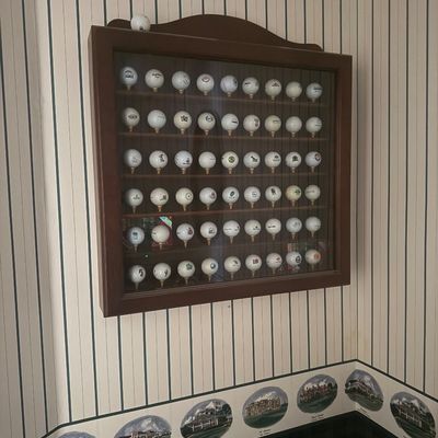 Sale Photo Thumbnail #116: Wall-mounted wooden display case filled with a collection of printed logo golf balls.