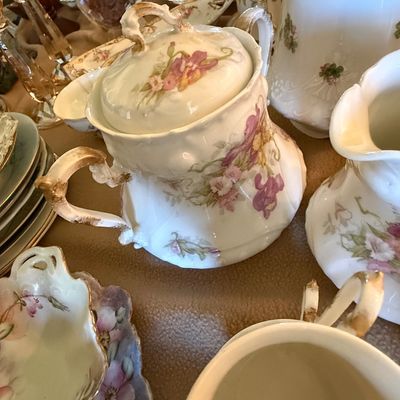 Sale Photo Thumbnail #45: Collection of antique porcelain tableware featuring floral motifs, gilded handles, and ornate detailing.