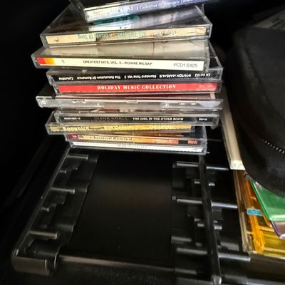 Sale Photo Thumbnail #75: Stack of audio CDs in jewel cases featuring artists such as Celine Dion, Wynton Marsalis, and Diana Krall, resting on a black storage tray.