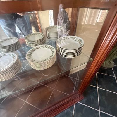 Sale Photo Thumbnail #152: Stacks of vintage Christmas holly pattern porcelain dinnerware displayed inside a glass-door wooden hutch.