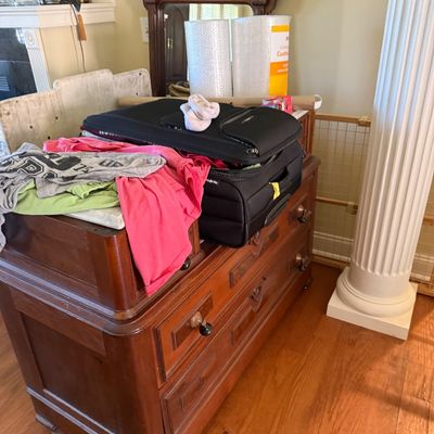 Sale Photo Thumbnail #31: Antique wooden dresser with turned knobs and a matching mirror, currently holding a black soft-sided suitcase and clothing.