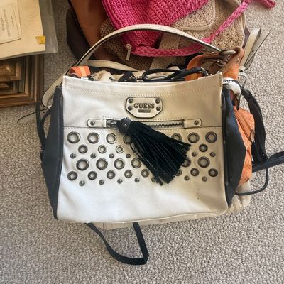 Sale Photo Thumbnail #177: White and black studded Guess handbag with tassel detail, surrounded by a pile of various women's purses.
