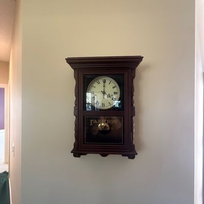 Sale Photo Thumbnail #158: Vintage dark wood Fashion Regulator wall clock featuring Roman numerals and a glass door displaying the pendulum.