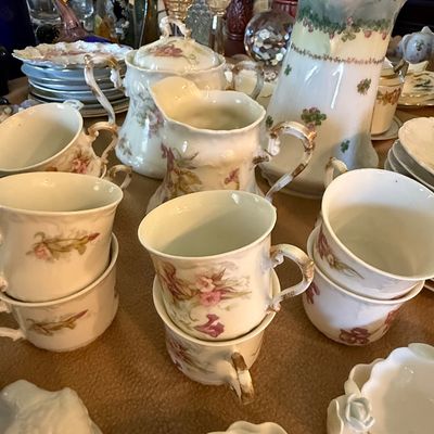 Sale Photo Thumbnail #47: Vintage floral porcelain tea set including stacked teacups, creamer, covered sugar bowl, and tall coffee pot with gilded accents.