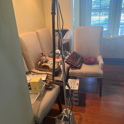 Sale Photo Thumbnail #104: Standing garment steamer with translucent water tank alongside upholstered high-back dining chairs.