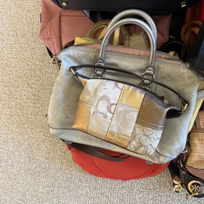 Sale Photo Thumbnail #28: Collection of designer handbags, featuring a silver Coach jacquard satchel with metallic trim alongside various leather totes and shoulder bags.
