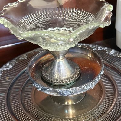 Sale Photo Thumbnail #52: Vintage glass epergne or pedestal dish with a ruffled edge and silver-plated base, displayed alongside additional tarnished silver-tone serving trays.