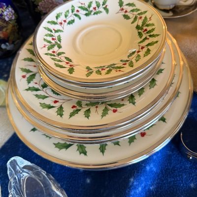 Sale Photo Thumbnail #40: Stack of Lenox Holiday collection porcelain plates featuring a green holly leaf motif and silver-tone trim.