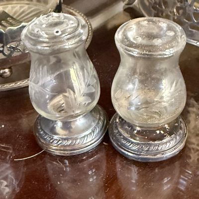 Sale Photo Thumbnail #53: Pair of vintage etched glass salt and pepper shakers with silver-tone weighted bases and integral glass tops.