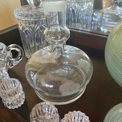 Sale Photo Thumbnail #108: Vintage etch-engraved clear glass decanter featuring floral motifs, displayed alongside cut crystal canisters and small salt cellars.