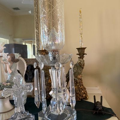 Sale Photo Thumbnail #32: Vintage crystal hurricane lamp featuring a cut glass shade and hanging prism accents, set alongside a lead crystal cross figurine.