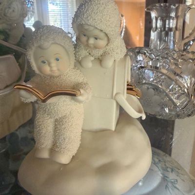 Sale Photo Thumbnail #105: Department 56 Snowbabies porcelain figurine featuring two children with gold-toned accents, displayed inside a glass cabinet.