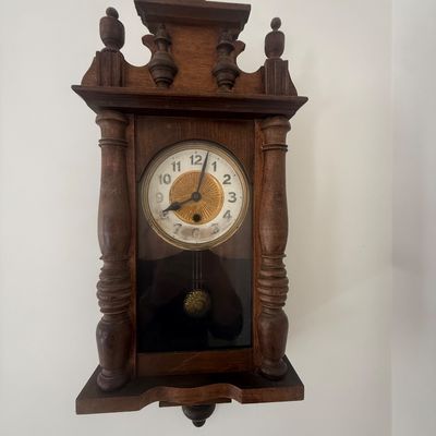 Sale Photo Thumbnail #8: Vintage dark wood wall clock featuring ornate turned columns, top finials, and a brass-accented clock face with pendulum.