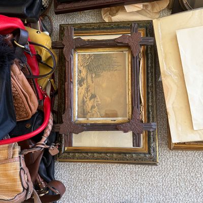 Sale Photo Thumbnail #26: Antique Adirondack-style carved wooden frame featuring leaf corner details, shown alongside assorted framed artwork and leather handbags.