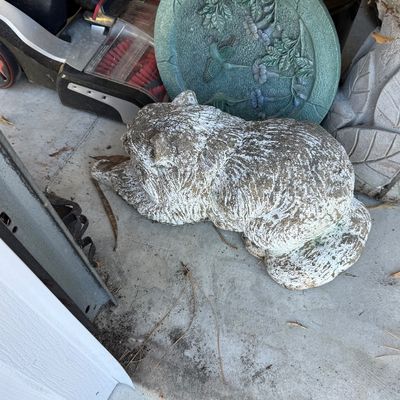 Sale Photo Thumbnail #98: Weathered concrete garden statue of a crouching cat, paired with a green decorative garden stepping stone featuring relief carvings of hummingbirds and flowers.
