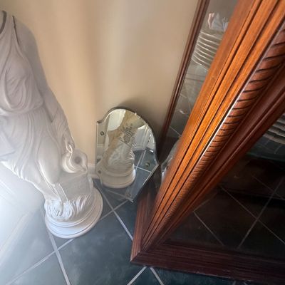 Sale Photo Thumbnail #156: Classical-style white statue of a draped female figure holding a pitcher, set alongside an etched frameless mirror and a large wooden frame.
