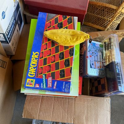 Sale Photo Thumbnail #92: Box of assorted games and household items including a Checkers board game, dominoes tin, a yellow zippered pouch, and a Hummel Gold Christmas Ornament Collection box.