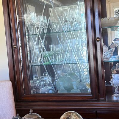 Sale Photo Thumbnail #46: Traditional dark wood china hutch with glass-front display doors featuring diamond mullions, filled with crystal stemware and glassware.