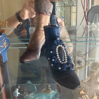 Sale Photo Thumbnail #123: Collection of decorative miniature resin shoe and boot figurines displayed on a glass shelf in a cabinet.