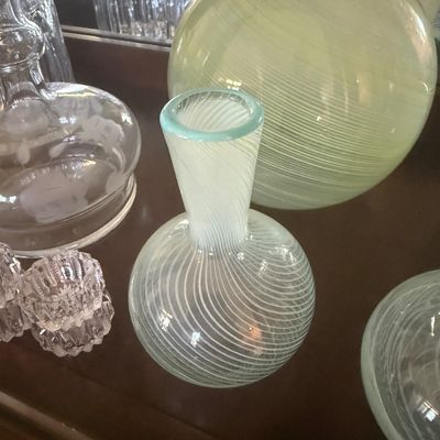Sale Photo Thumbnail #109: Collection of art glass and crystal pieces, including a swirled pale green glass vase with a light blue rim alongside cut glass decanters and dishes.