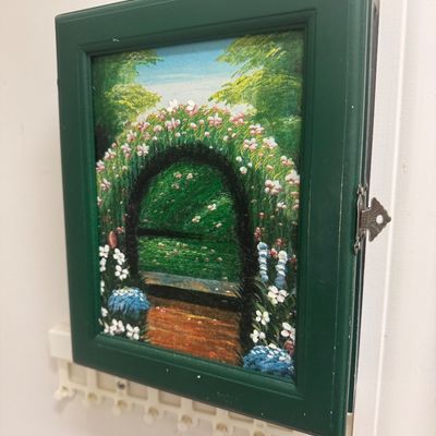 Sale Photo Thumbnail #101: Wall-mounted dark green wooden key cabinet featuring a hand-painted floral garden scene on the front door.