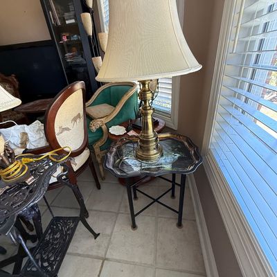 Sale Photo Thumbnail #65: Traditional brass column table lamp with a tall pleated fabric shade, set atop a black metal side table.