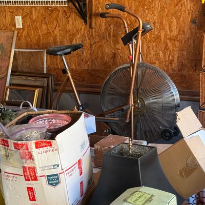 Sale Photo Thumbnail #94: Vintage Schwinn Airdyne exercise bike set behind cardboard storage boxes and household goods.