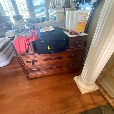 Sale Photo Thumbnail #161: Antique wooden dresser with marble-top side drawers and brass keyhole escutcheons, stacked with luggage and household goods.
