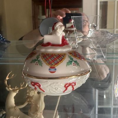 Sale Photo Thumbnail #127: Vintage porcelain holiday lidded trinket dish featuring a Santa dog finial, gold rim accents, and Christmas motifs.