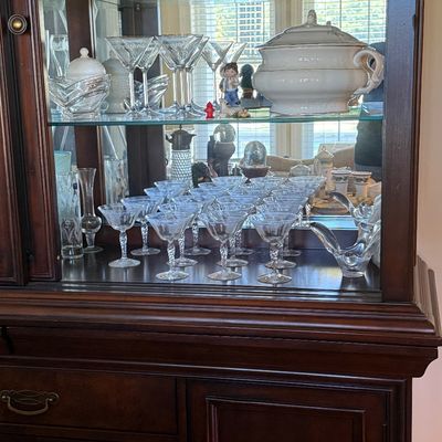 Sale Photo Thumbnail #50: Traditional dark wood china cabinet with mirrored back and glass shelves, filled with cut crystal glassware, etched stemware, and a porcelain covered tureen.