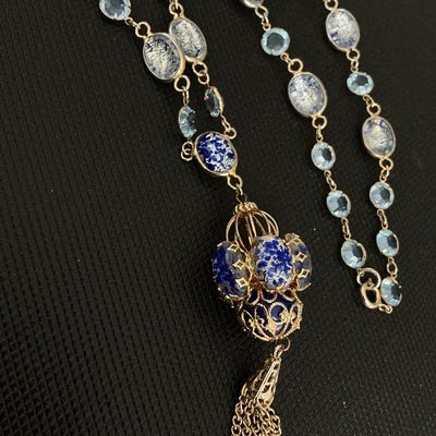 Sale Photo Thumbnail #151: Ornate vintage costume necklace featuring blue and silver foil art glass beads, light blue bezel-set crystals, and a detailed cage-style pendant with hanging chain tassel. Gold-tone chain settings with spring ring clasp closure. Excellent vintage conditio